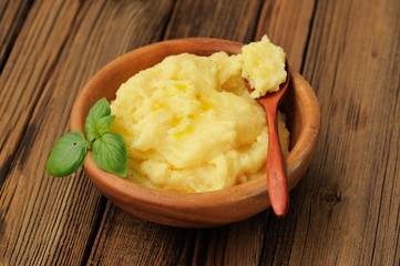 Polenta with green basil in wooden bowl with wooden spoon