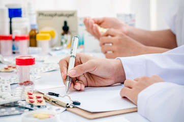 Obraz na płótnie Canvas two pharmacists preparing prescription and pill container