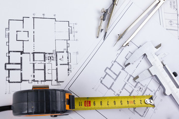 Architectural project, blueprints, blueprint rolls and divider compass, calipers, folding ruler on plans Engineering tools view from the top. Copy space. Construction background.