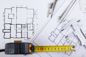 Architectural project, blueprints, blueprint rolls and divider compass, calipers, folding ruler on plans Engineering tools view from the top. Copy space. Construction background.