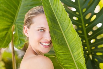  Beautiful blonde smiling at camera behind leaf