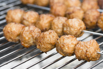 BBQ Meatballs - Meatballs on metal skewers being grilled on a barbecue.
