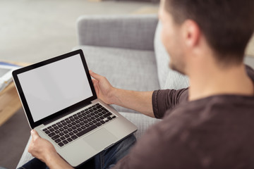 mann sitzt auf dem sofa und schaut auf notebook