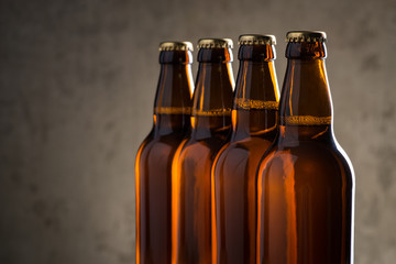 Freshly brewed beer bottles in a row over the grey concrete wall