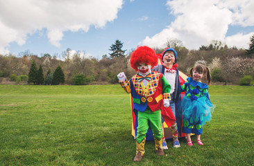 Three children standing in a garden dressed as clowns