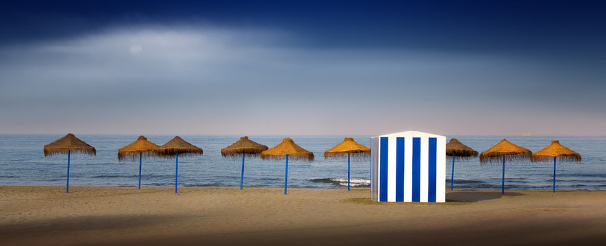 Beach hut and beach umbrellas in a row, Valencia, Spain