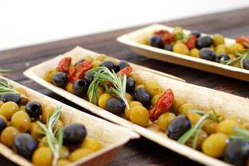 black and green olives, herbs, sun-dried tomatoes in an oblong d