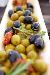 black and green olives, herbs, sun-dried tomatoes in an oblong d