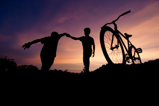 Wide moving silhouettes of two boys holding hands