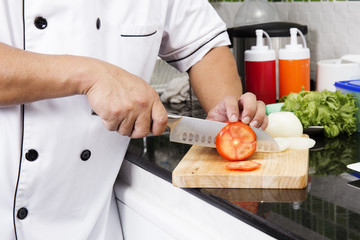 Chef's hands cutting Tomato