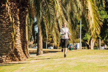 Fototapeta na wymiar Healthy lifestyle young sporty woman jogging at tropical park