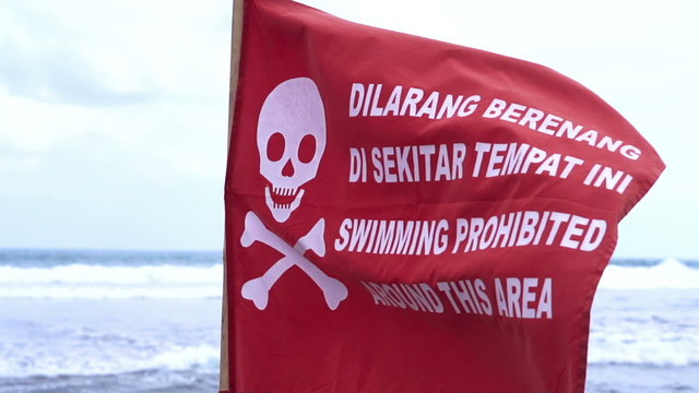 Red flag with death skull fluttering on beach, slow motion shot at 240fps
