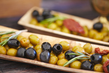 black and green olives, herbs, sun-dried tomatoes in an oblong d