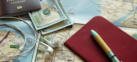 Travel stuff,  passport, money, earphone, notebook on the map