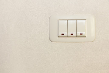 Threefold multiply light switch on white wall.