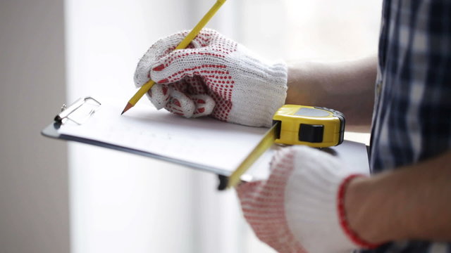 close up of man with measuring ruler and clipboard