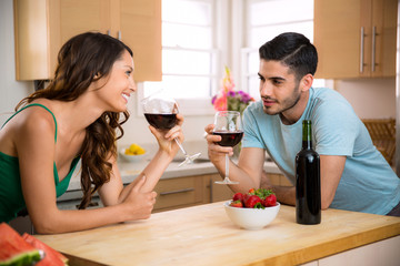 Male and female sipping red wine in the kitchen sharing a romantic gaze with chemistry