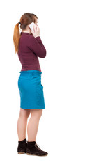 Fototapeta premium back view of standing young beautiful woman and using a mobile