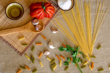 Uncooked dry spaghetti on a rustic surfaces with tomato, garlic,