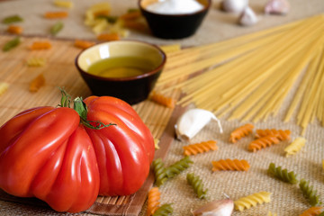 Uncooked dry spaghetti on a rustic surfaces with tomato, garlic,