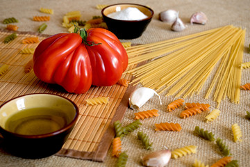 Uncooked dry spaghetti on a rustic surfaces with tomato, garlic,