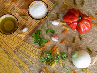 Uncooked dry spaghetti on a rustic surfaces with tomato, garlic,