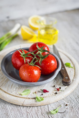 fresh tomatoes on a vintage plate on a light wooden background