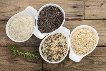 Verschiedene Reissorten in Porzelanschalen auf rustikalem Holzbrett