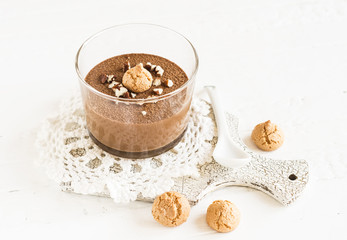 chocolate mousse with nuts and biscuits in a glass beaker on a white surface