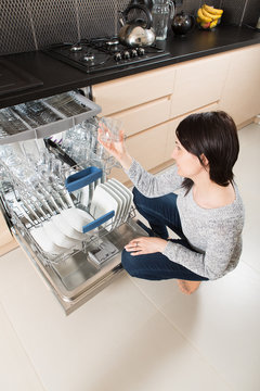 Woman using a dishwasher in a modern kitchen.