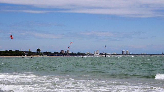 group of kite surfers in front of skyscrapers
