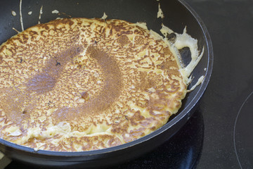 making pancakes in a black pan, fried until golden brown