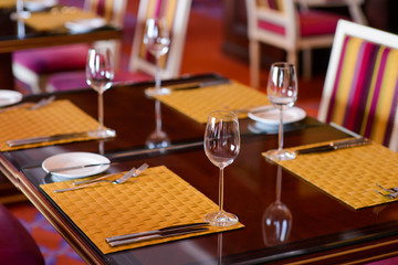 Served wooden table in a restaurant/Wooden table in a restaurant with empty wine glasses and napkins