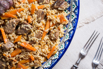 Pilaf in handmade plate on wooden background