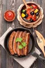 Grilled homemade sausages in a frying pan and salad fresh vegetables