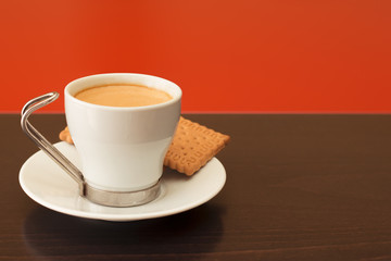 Coffee cup and cookies hover a wooden and red table