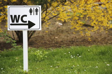 Sign for toilet on metal board in nature