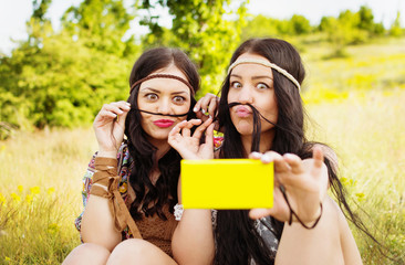Two happy young boho women having fun taking a selfie