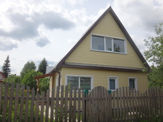 Дачный домик желтого цвета за забором
