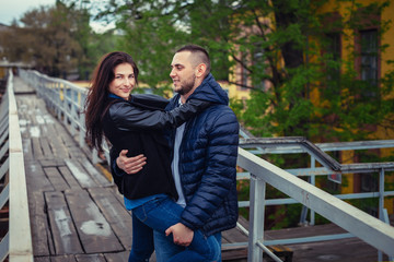Fototapeta premium Beautiful young couple in love on a date outdoors on modern urban background. Smiling and hugging. Bearded handsome rustic man and brunette pretty woman in casual dress.