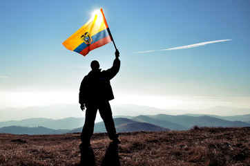 successfull silhouette man winner waving Ecuador flag on top of the mountain peak