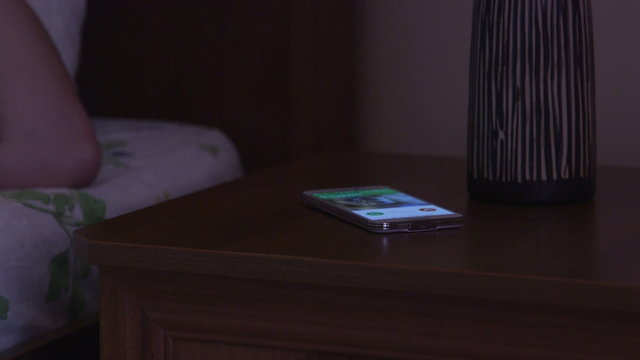 Sleeping woman on bed awakened by smart phone incoming call at night