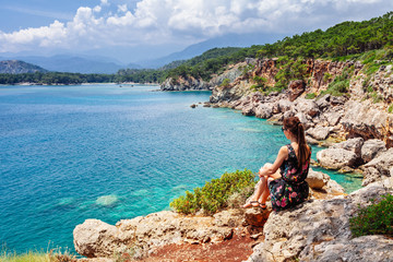 Tourist girl sitting and looking on bay of old greek town Phaselis. Panoramic view on coast near...