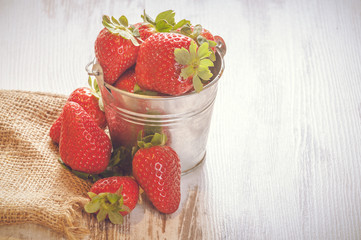 Spring fruits, strawberries in an aluminum bucket on a vintage w