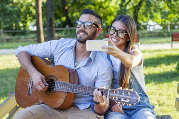 young couple in love takes a selfie while plays guitar