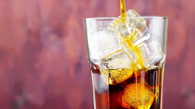 pouring fresh coke with ice cubes on wood background, summer time concept