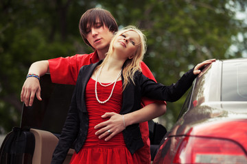 Happy young fashion couple in love by new car