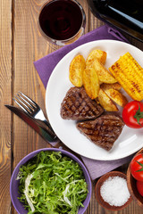 Steak with grilled potato, corn, salad and red wine