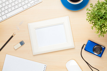 Photo frame on office table with notepad, computer and camera