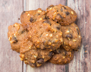 Homemade chocolate chip cookies over weathered wooden surface.